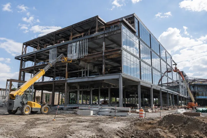 Commercial steel-framed building under construction with glazing and access equipment