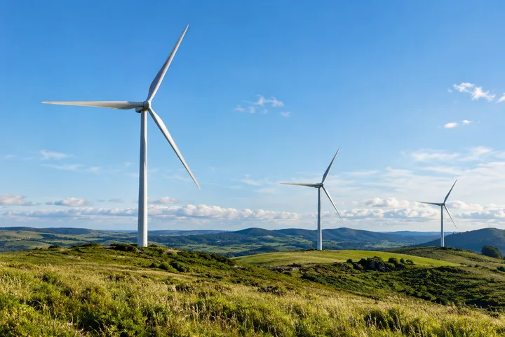 Three wind turbines above rolling grassland